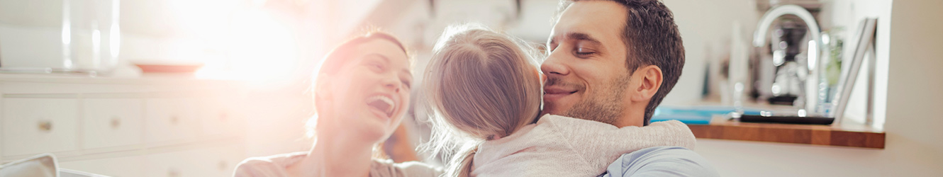 Family laughing and hugging in their kitchen