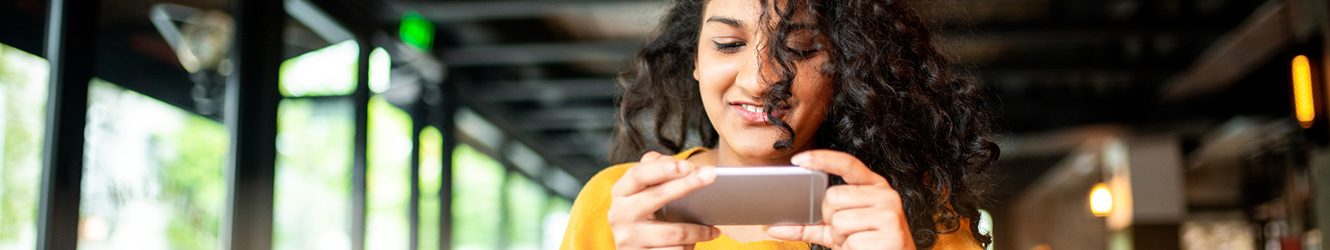 Lady in a restaurant using smartphone for mobile deposit